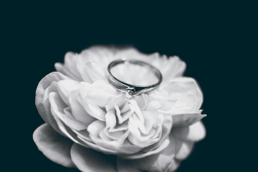 A beautiful silver ring placed delicately on a white rose, symbolizing romance and commitment.